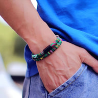 Bracelet cordon double vert à motifs bohèmes portés sur poignet d'homme avec t-shirt bleu et jean clair.