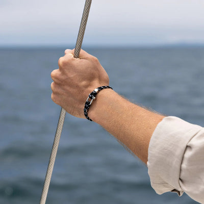 Bracelet cordon double noir à motifs avec mousqueton en acier inoxydable porté au poignet homme.