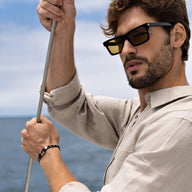 Bracelet cordon double bleu marin avec mousqueton en acier inoxydable porté homme près de la mer.