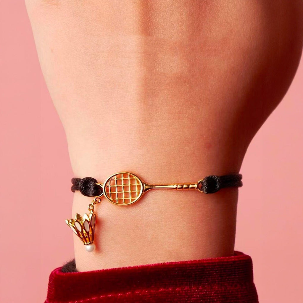 Bracelet cordon noir avec pendentifs en acier inoxydable doré, raquette et volant de badminton.