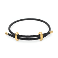 Bracelet cordon noir avec accents en acier inoxydable doré au design minimaliste et authentique.