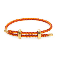 Bracelet cordon tressé orange et rouge avec accents en acier inoxydable doré, style minimaliste.