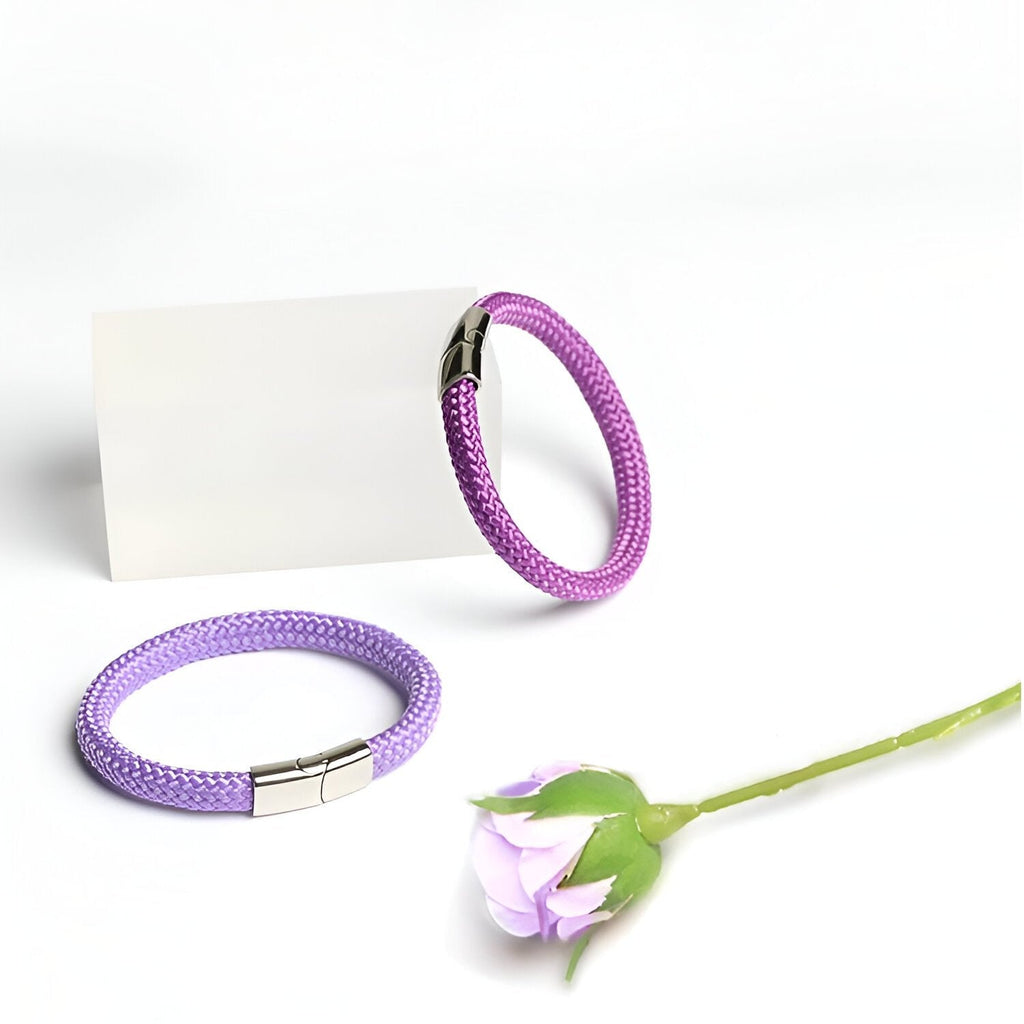 Bracelet cordon violet en corde de bateau avec fermoir acier inoxydable, modèle Elwan, posé avec une fleur lavande claire.
