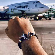 Bracelet cordon noir avec avion en acier inoxydable argenté, style moderne et masculin.