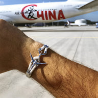 Bracelet cordon bleu avec avion en acier inoxydable sur poignet masculin.