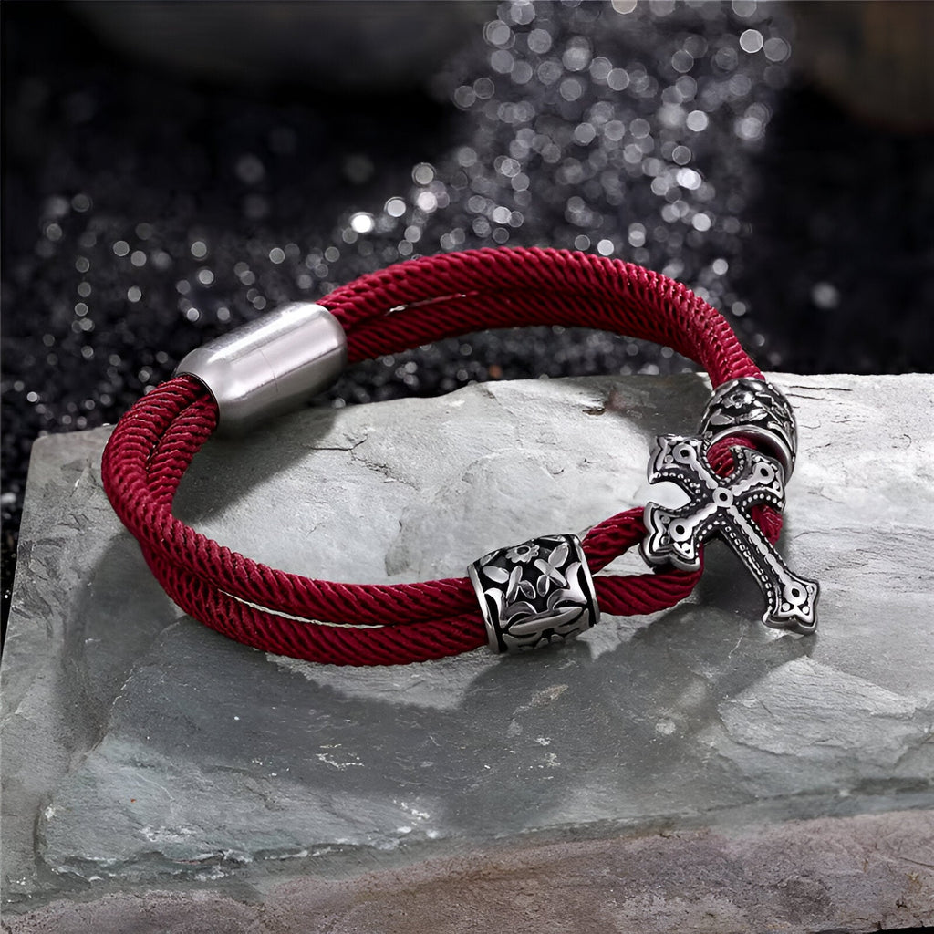 Bracelet cordon bordeaux en coton avec croix chrétienne en acier inoxydable et détail ornemental.