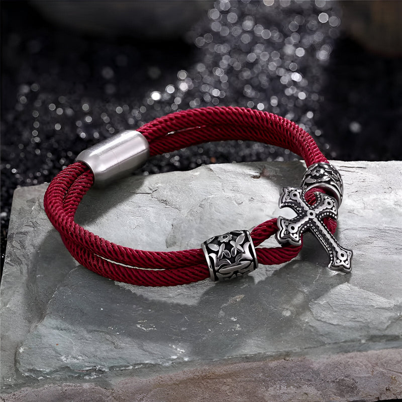 Bracelet cordon bordeaux en coton avec croix chrétienne en acier inoxydable et détail ornemental.