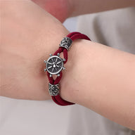 Bracelet cordon bordeaux en coton avec gouvernail en acier inoxydable et détails sculptés argentés.