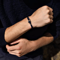 Bracelet cordon en cuir bleu avec mousqueton en acier inoxydable porté au poignet homme.