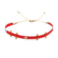 Bracelet cordon rouge en polyester-coton avec perles de verre japonaises dorées et fermeture ajustable.