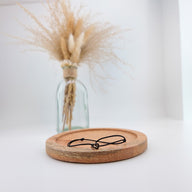 Bracelet cordon noir avec pendentif fer à cheval en acier inoxydable, fini brillant, style porte-bonheur, posé sur plateau.