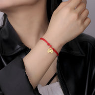 Bracelet cordon rouge avec pendentif fer à cheval en acier inoxydable porté au poignet féminin.
