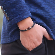 Bracelet cordon noir en corde avec fermoir magnétique argenté, porté au poignet homme.