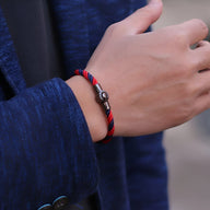 Bracelet cordon bicolore rouge et bleu avec fermoir magnétique métallique sur poignet homme.