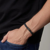 Bracelet cordon noir fin avec plaque en acier inoxydable gravée, style discret et moderne.