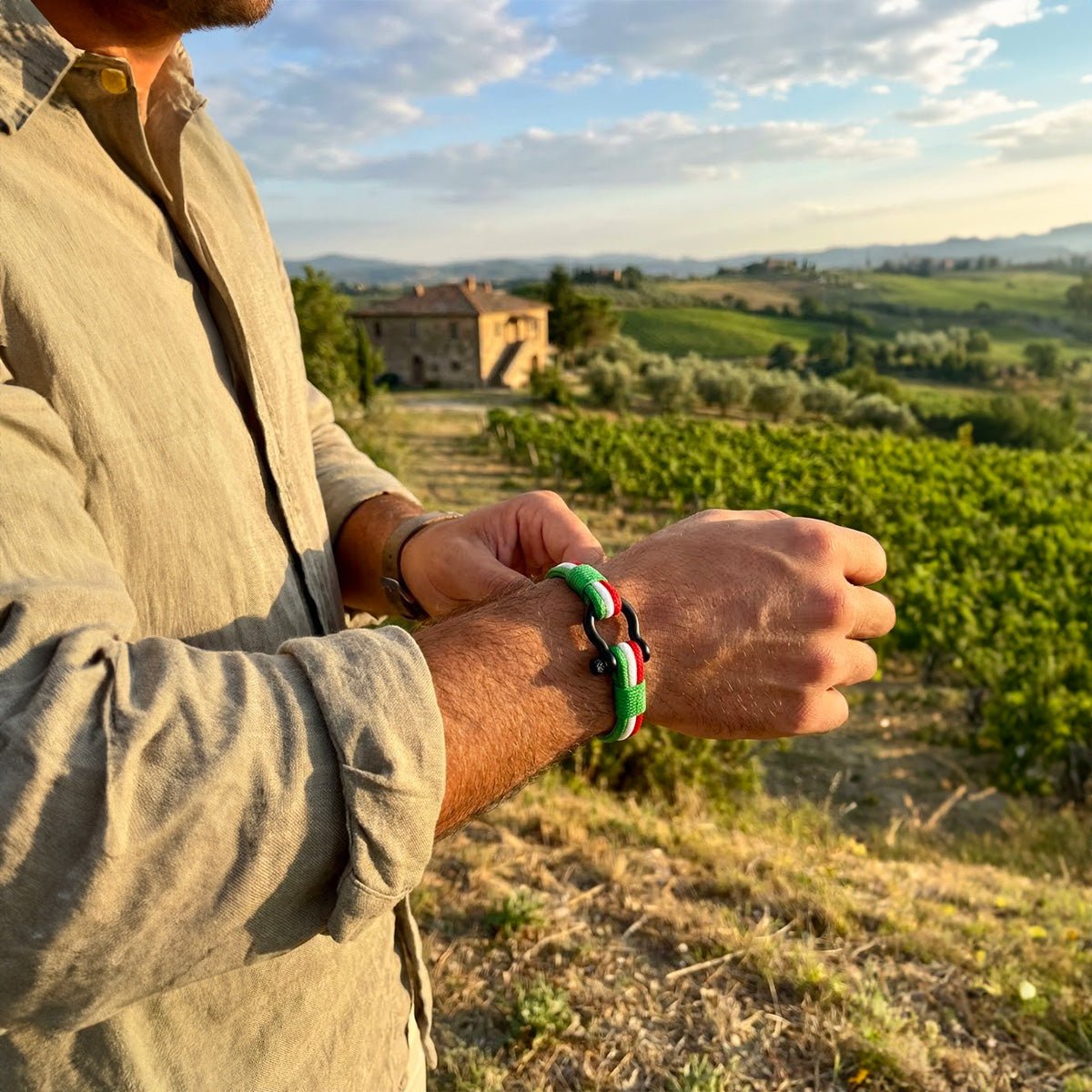 Bracelet cordon tricolore vert blanc rouge avec mousqueton en acier inoxydable porté au poignet masculin dans un paysage.