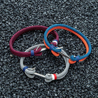 Trois bracelets cordon marin avec ancre acier inoxydable, couleurs bordeaux, gris et bleu-orange, tressés et ajustables.