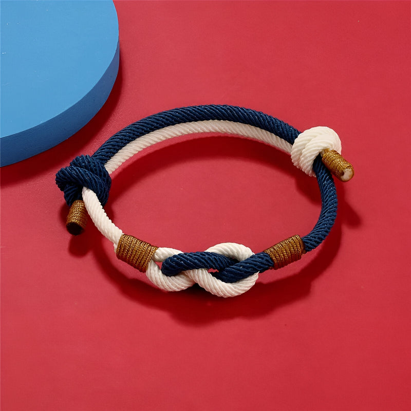 Bracelet cordon bicolore bleu et blanc à nœud central et détails marron.