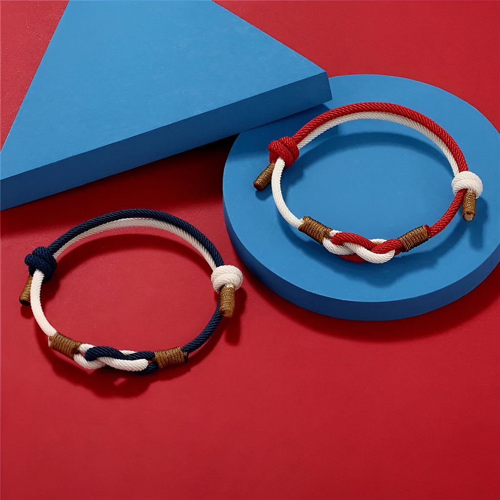 Bracelet cordon bi-colore bleu et rouge à nœud central avec détails en cuir marron et blanc.
