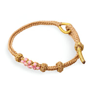 Bracelet cordon beige avec motif floral rose et fermoir anneau doré.