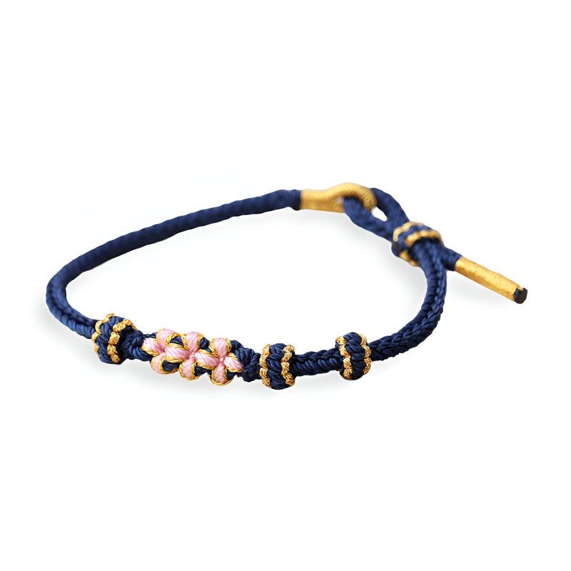 Bracelet cordon bleu foncé avec motif floral rose et blanc en perles, fermoir doré.