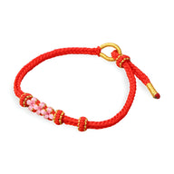 Bracelet cordon rouge avec motif floral rose et fermoir doré.
