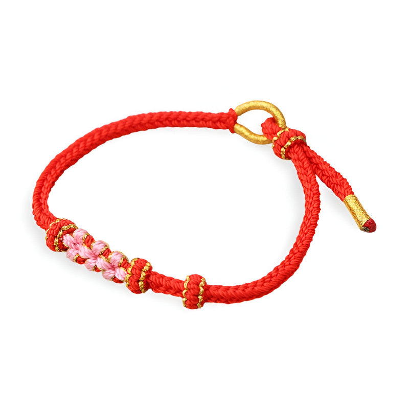 Bracelet cordon rouge avec motif floral rose et fermoir doré.