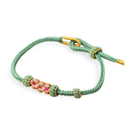 Bracelet cordon vert avec motif floral rose et détails dorés délicats.