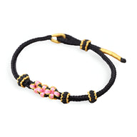 Bracelet cordon noir avec motif floral rose et détails jaunes, style délicat pour femme.