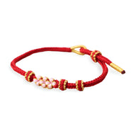 Bracelet cordon rouge pour femme avec motif floral rose et fermoir doré.