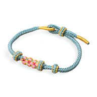 Bracelet cordon bleu clair avec motif floral rose et jaune, fermoir ajustable doré.