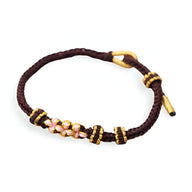 Bracelet cordon marron avec motif floral en perles roses et détails jaunes.