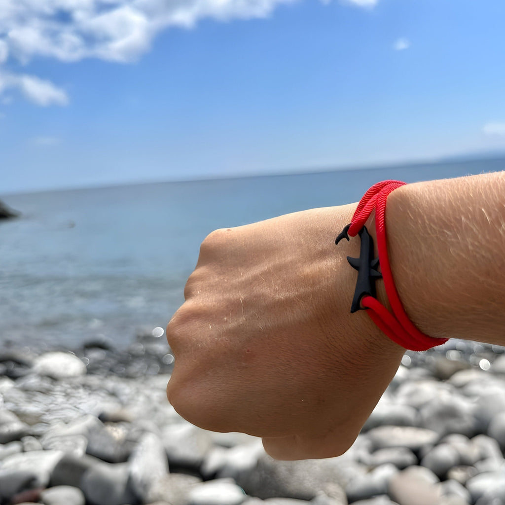 Bracelet cordon rouge avec motif requin noir, style moderne et minimaliste.