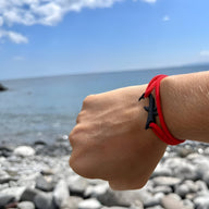 Bracelet cordon rouge avec motif requin noir, style moderne et minimaliste.