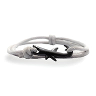 Bracelet cordon blanc avec pendentif requin noir stylisé et fermoir noeud coulissant.