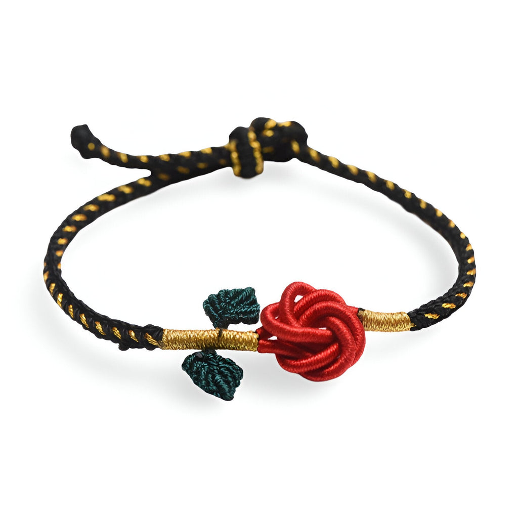 Bracelet cordon noir avec motif rose rouge nouée et deux feuilles vert foncé, détails dorés.