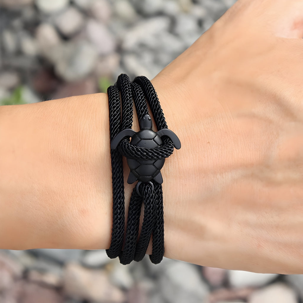 Bracelet cordon noir avec motif tortue en relief, style moderne et épuré.