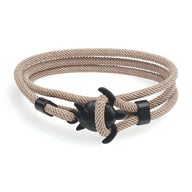 Bracelet cordon beige avec fermoir ancre noire et motif tortue élégant.