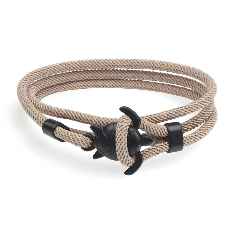 Bracelet cordon beige avec fermoir ancre noire et motif tortue élégant.