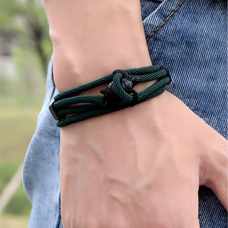 Bracelet cordon vert sapin avec motif tortue et nœud double style Franklin, porté au poignet.