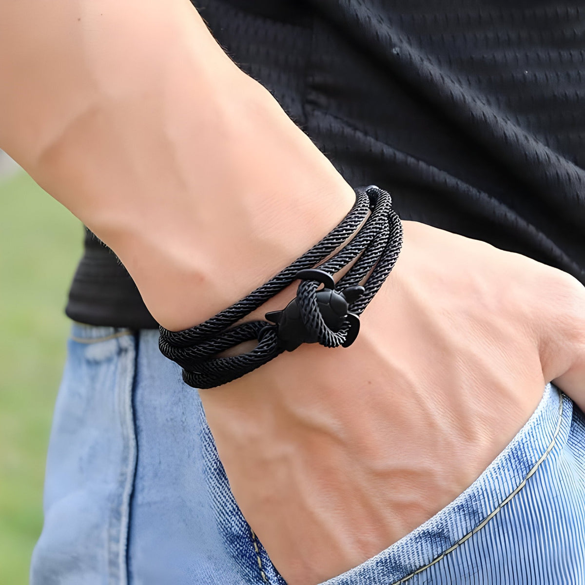 Bracelet cordon noir avec motif tortue en nœud sur poignet, style décontracté.