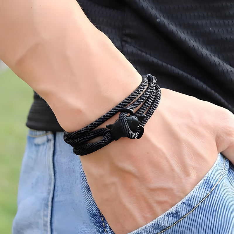 Bracelet cordon noir avec motif tortue en nœud sur poignet, style décontracté.