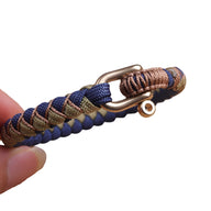 Bracelet cordon en paracorde bleu et beige avec mousqueton bronze, fermoir ajustable.