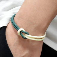Bracelet cordon bi-colore bleu marine et blanc avec noeud simple sur poignet.