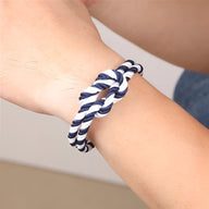 Bracelet cordon épais bleu et blanc tressé avec noeud sur poignet peau claire.