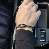 Bracelet cordon gris à noeud en argent sterling 925 porté au poignet, style unisexe élégant.