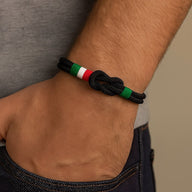 Bracelet cordon noir avec nœud marin et détail drapeau italien vert, blanc, rouge, porté au poignet.