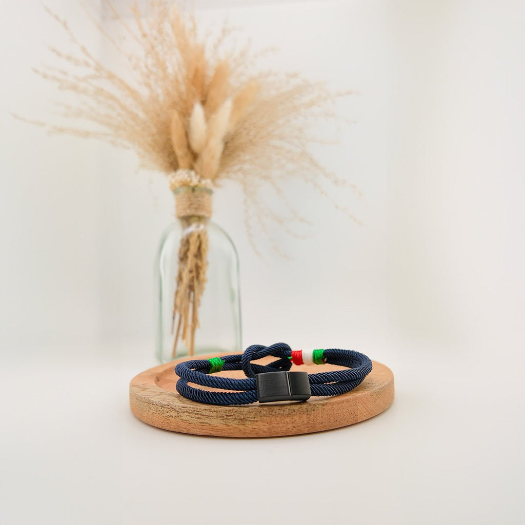 Bracelet cordon bleu marine avec nœud marin et détails vert, blanc, rouge rappelant le drapeau italien, fermoir noir mat.