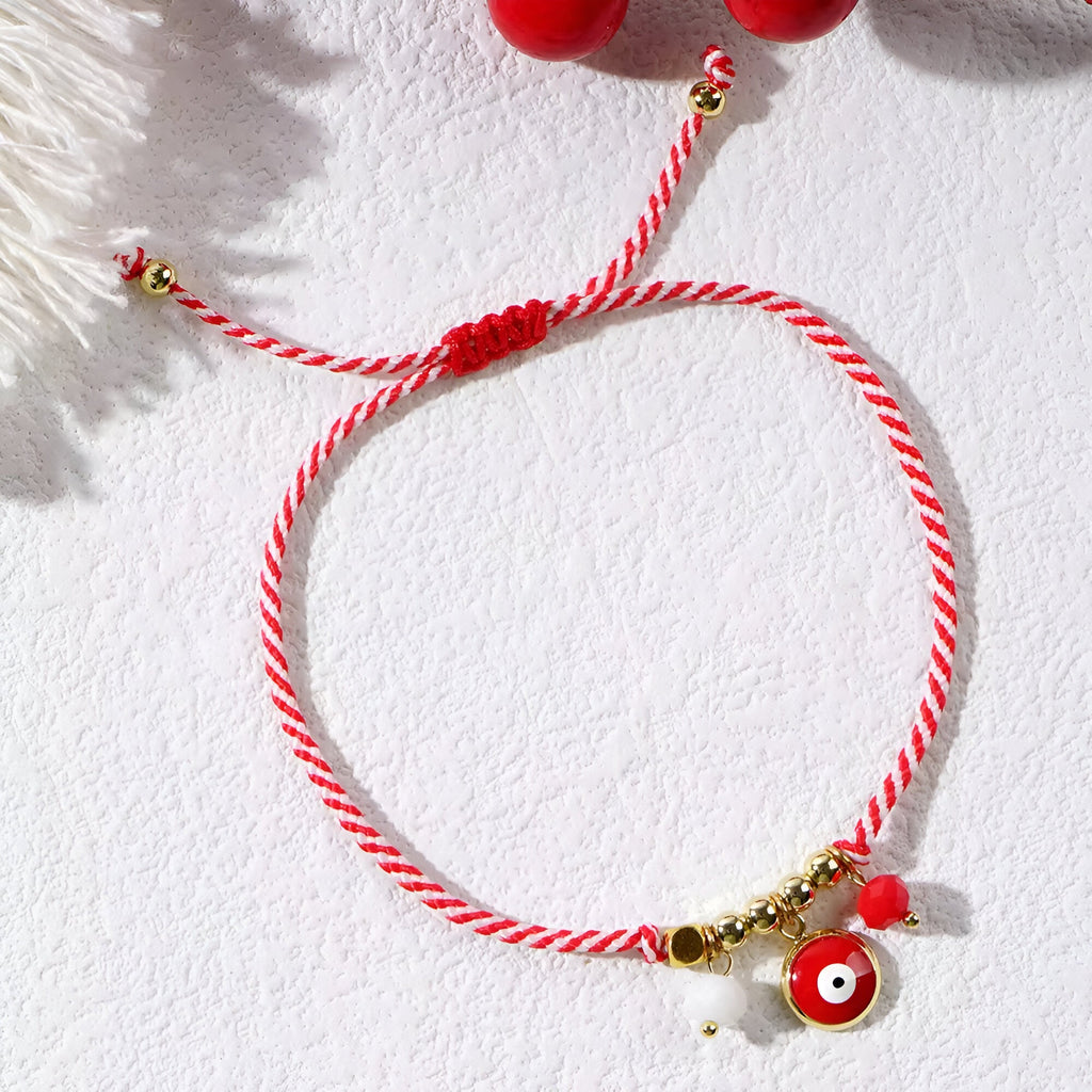 Bracelet cordon rouge tressé avec pendentifs or et œil de dzi rouge pour femme.