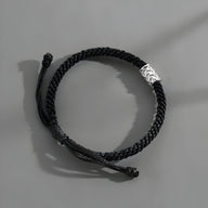 Bracelet cordon noir tressé avec ornement cylindrique en argent pour homme.